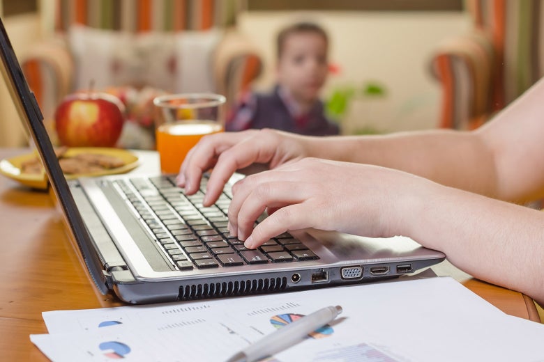 A woman doing work while her son looks on in the background.